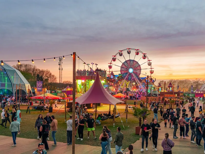 Obiskovalci festivala ob sončnem zahodu, v ozadju panoramsko kolo